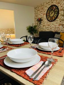 een tafel met witte borden en glazen en een klok bij Casa Grande in Romilly-sur-Seine