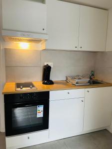 een keuken met witte kasten en een zwarte oven bij Casa Grande in Romilly-sur-Seine