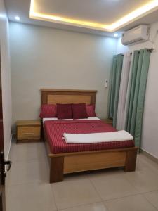 ダカールにあるresidence mounaのベッドルーム1室(赤いシーツと緑のカーテンが備わるベッド1台付)