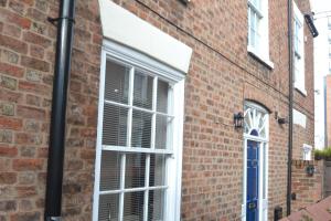 a brick house with white windows and a blue door at Charming 1 bed Georgian Apartment in Chester