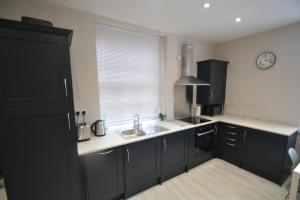 uma cozinha com armários pretos, um lavatório e uma janela em Charming 1 bed Georgian Apartment em Chester
