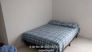 ein Schlafzimmer mit einem Bett mit einer karierten Decke und Kissen in der Unterkunft Lar Jampa - Casa para Temporada in João Pessoa