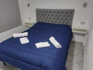 Una cama azul con dos toallas blancas. en costanera departamento en Viedma