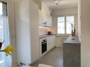 Una cocina con gabinetes blancos y encimera. en Casa Fiorella, en Nago-Torbole