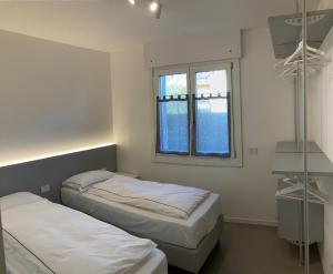 Un dormitorio con dos camas y una ventana. en Casa Fiorella, en Nago-Torbole