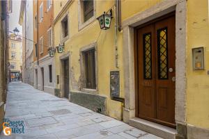 un vicolo con una porta marrone su un edificio giallo di Azzurro a Trieste