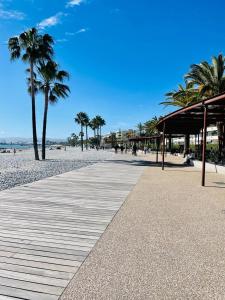 a boardwalk on a beach with palm trees at Studio Cosy avec terrasse Saint-Laurent du Var limite Nice in Saint-Laurent-du-Var