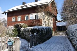 ein Haus mit einem Zaun im Schnee in der Unterkunft Gästehaus Werner in Lenggries