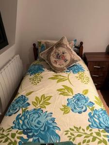 a bed with a blanket with blue flowers on it at 009- Studio apartment in Ealing F5 in Ealing