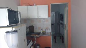 una pequeña cocina con armarios blancos y fregadero en Lar Jampa Beach en Cabedelo