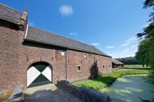 a red brick barn with a white door next to a river at Terborgh Budget in Schinnen