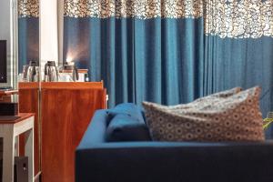 PALM Springs Bed & Breakfast في يمبي: غرفة معيشة مع أريكة زرقاء وستائر زرقاء