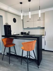 a kitchen with two bar stools and a counter at Maia Grand Studio Bucharest in Bucharest