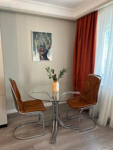 a glass table and two chairs in a room at Maia Grand Studio Bucharest in Bucharest