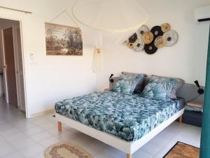 a bedroom with a bed with a blue comforter at Appartement avec piscine et accès direct plage 102 in Folle Anse +8 photos