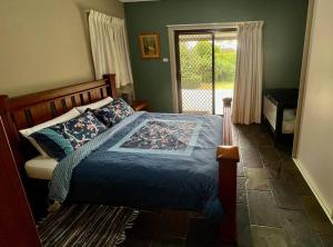 a bedroom with a bed with a blue blanket and a window at Beautiful 1960s home in historic Yackandandah in Yackandandah