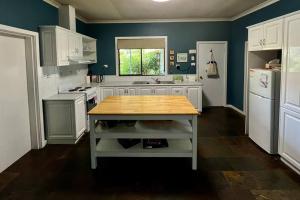 a kitchen with white cabinets and a wooden counter top at Beautiful 1960s home in historic Yackandandah in Yackandandah