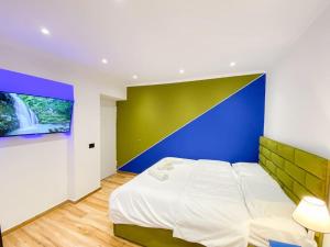 um quarto com uma cama branca e uma parede azul e verde em City Center 12 - Tirana Way Apartments em Tirana