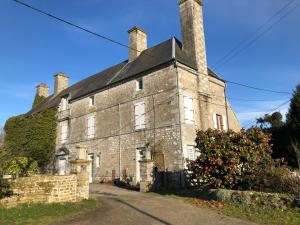 an old stone building with two chimneys on top at Le Logis du Gast chambre verte in Le Gast