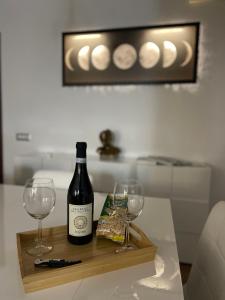 Una botella de vino y dos copas en una bandeja de madera. en MiCasaEsTuCasa, en Porto Santo Stefano