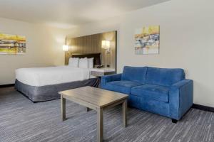 a hotel room with a bed and a blue couch at Best Western Plus Renton Inn in Renton