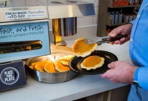 a man is holding a spatula and flipping pancakes at Sonesta ES Suites Raleigh Cary in Cary