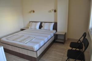 a bedroom with a bed and two chairs in it at Vila RAZA - locatie centrala in Eforie Nord