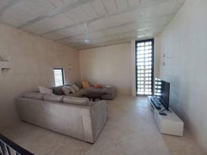 a large living room with a couch and a tv at Casa Manuela: Espectacular villa al frente del mar in Sisal