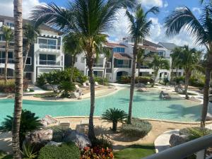 a swimming pool with palm trees in front of a building at Esmeralda67 Tamarindo in Bayahibe