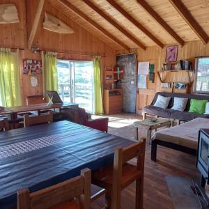 een woonkamer met een grote houten tafel en een bank bij EKILIBRE Surf Eco Hostal in Curanipe