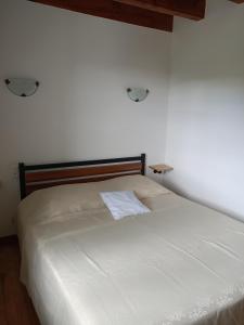 a bedroom with a white bed with two lights on the wall at La Vallée in Lacrouzette