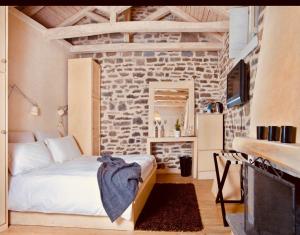 a bedroom with a bed and a stone wall at Mikro Papigo 1700 Hotel & Spa in Papingo