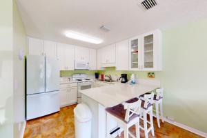 cocina con armarios blancos y nevera blanca en Wendwood Condominiums F2 en Panama City Beach
