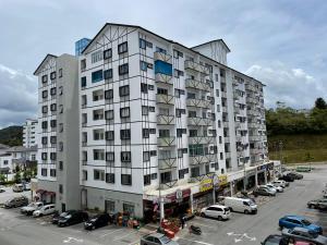 Un gran edificio blanco con coches aparcados en un estacionamiento. en Cameron Lavender Homestay, en Cameron Highlands