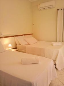 two beds in a room with white sheets at Pousada Aruamar in Aracaju