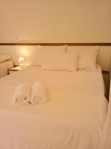 Una cama blanca con dos toallas. en Pousada Aruamar en Aracajú
