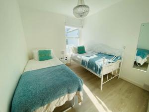 a bedroom with two beds and a mirror at Cowes Cottage in Cowes
