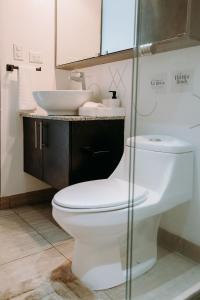 a bathroom with a white toilet and a sink at Wabi Salvi Apartment-A senses experience. in San Salvador