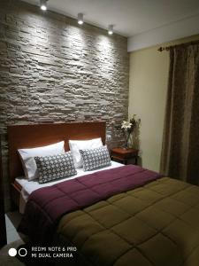 1 dormitorio con 1 cama grande y pared de piedra en Chrysanty's tea house, en Kalambaka