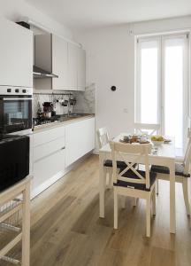 cocina con armarios blancos, mesa y sillas en Primaticcio 6, en Milán