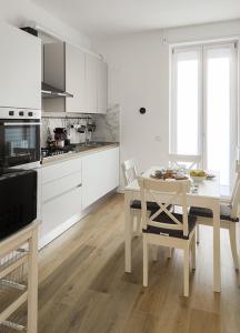 Una cocina con gabinetes blancos y una mesa y sillas. en Primaticcio 6, en Milán