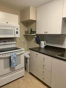 cocina con armarios blancos y microondas blanco en Cozy 1-bedroom in Bauer Terrace next to Citadel, en Halifax