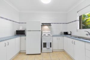 a white kitchen with white appliances and a window at Dolphin View on South Esplanade in Bongaree