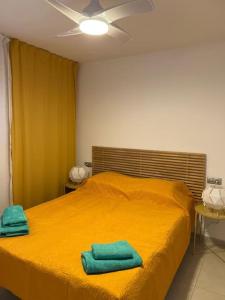 - une chambre avec un lit jaune et 2 serviettes dans l'établissement Parque Royal Costa Adeje, à Adeje