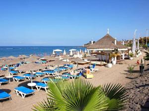 einen Strand mit Liegestühlen und Sonnenschirmen und dem Meer in der Unterkunft Parque Royal Costa Adeje in Adeje