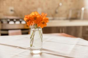 un jarrón lleno de flores naranjas sentado en una mesa en Chalés Vale da Lua, en Gonçalves