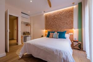 a bedroom with a large white bed with blue pillows at Vestal Suites Domo in Cambrils