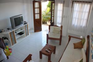 uma sala de estar com uma televisão, uma cadeira e uma mesa em Paraiso Moradas em Porto Seguro