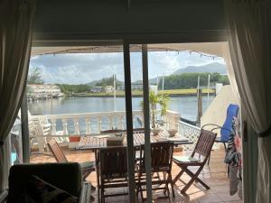 einen Balkon mit einem Tisch und Stühlen sowie Blick auf das Wasser in der Unterkunft Sunny Villa in the Marina - Excellent Water Views in Jolly Harbour