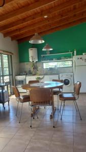 una cocina con mesa, sillas y una pared verde en Las Guardia en Cortaderas